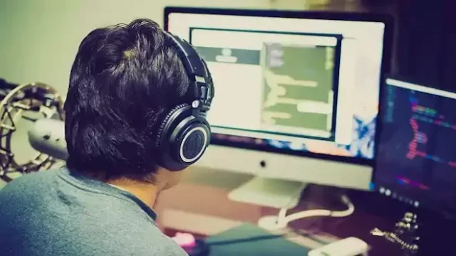 Egy férfi fülhallgatóval számítógép monitor előtt